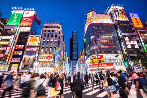 Busy crosswalk in front of buildings with many Japanese advertisement signs