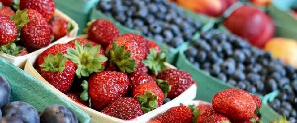 Local strawberries, blueberries and peaches at a farmers market stand.