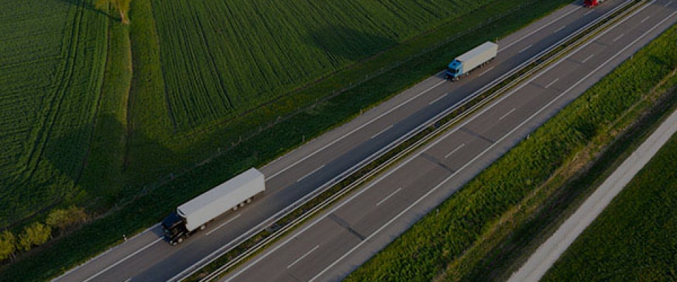 Heavy freight transport - aerial view of trucks speeding on a rural road.